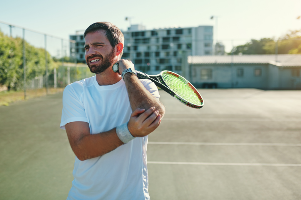 Un joueur de tennis tient sa raquette et frotte son coude