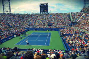 Match d'exhibition qui se déroule dans un grand stade de tennis avec le public